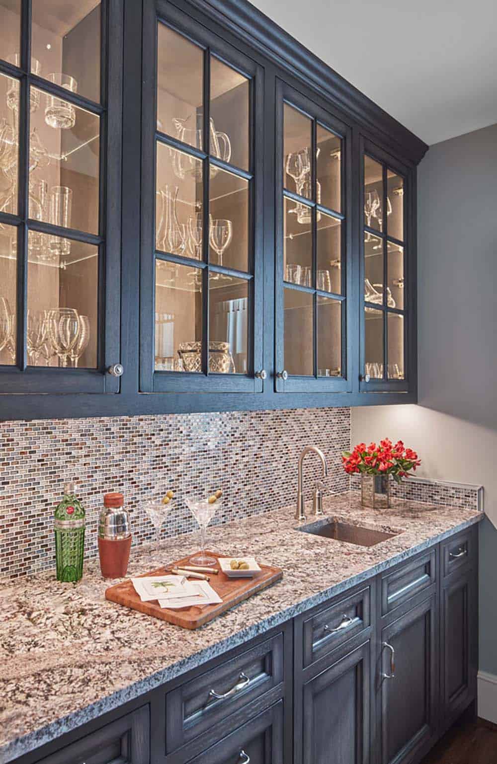 Historic waterfront house wet bar with navy blue glass-front cabinetry, mosaic tile backsplash and granite countertop in Maryland