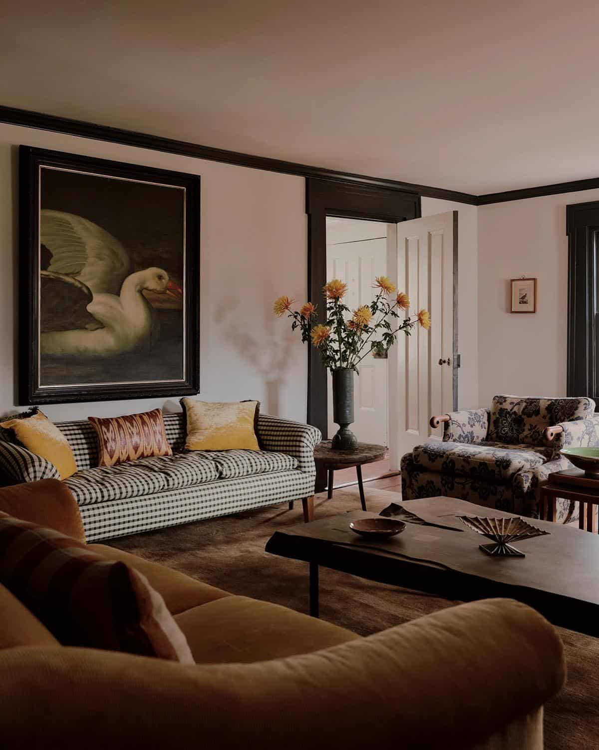 Living room with gingham sofa, camel velvet chair, large bird painting, and mixed-pattern upholstery