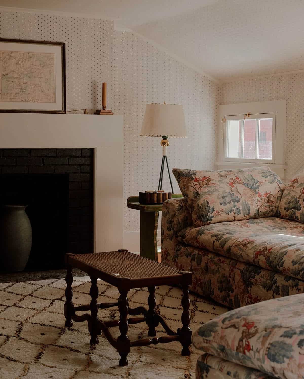 Cozy sitting room with hunting scene sofa, fireplace, antique cane bench, dotted wallpaper, and tripod lamp