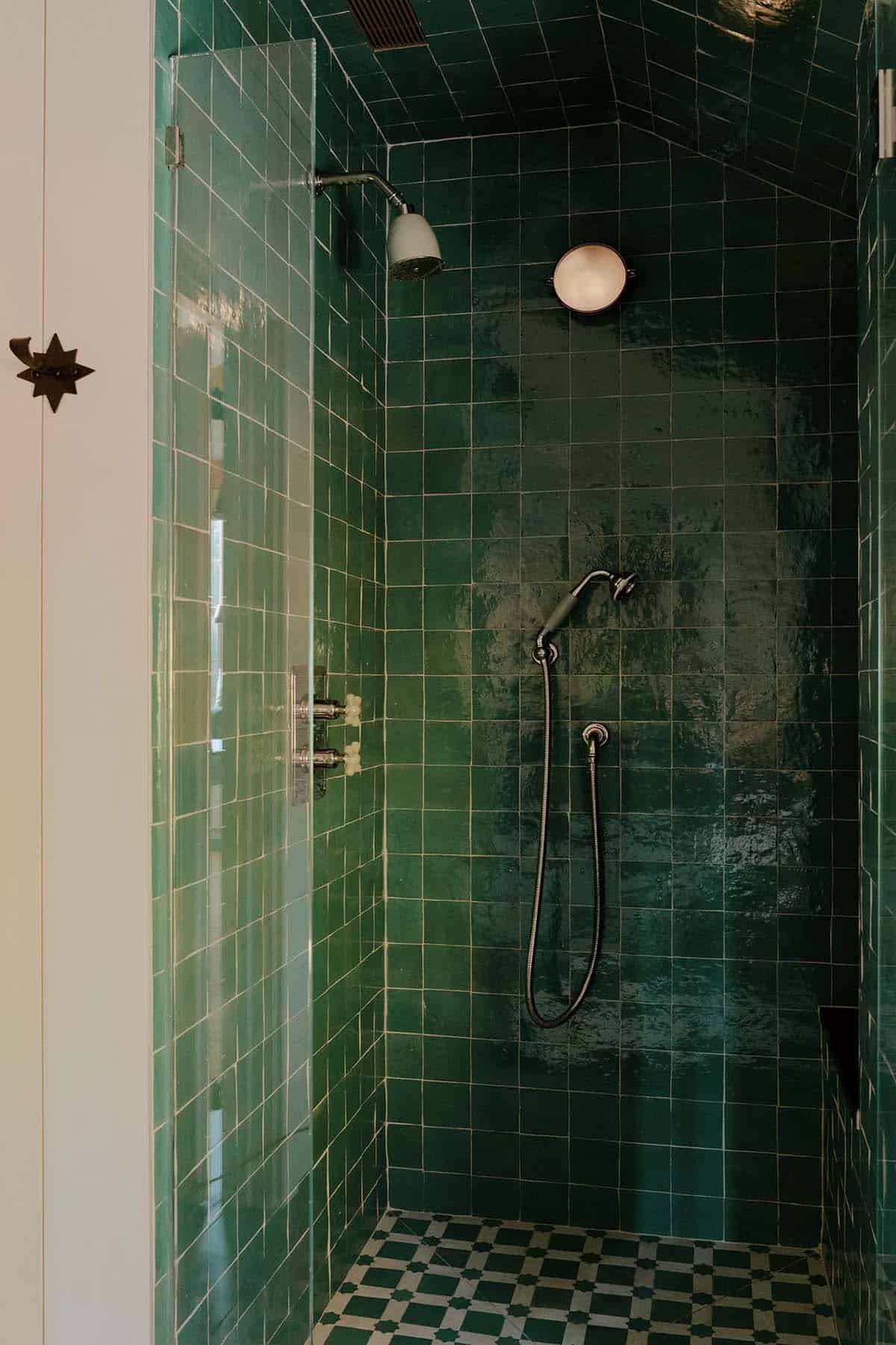 Shower enclosure fully tiled in deep forest green zellige with chrome fixtures and green-and-white checkerboard floor