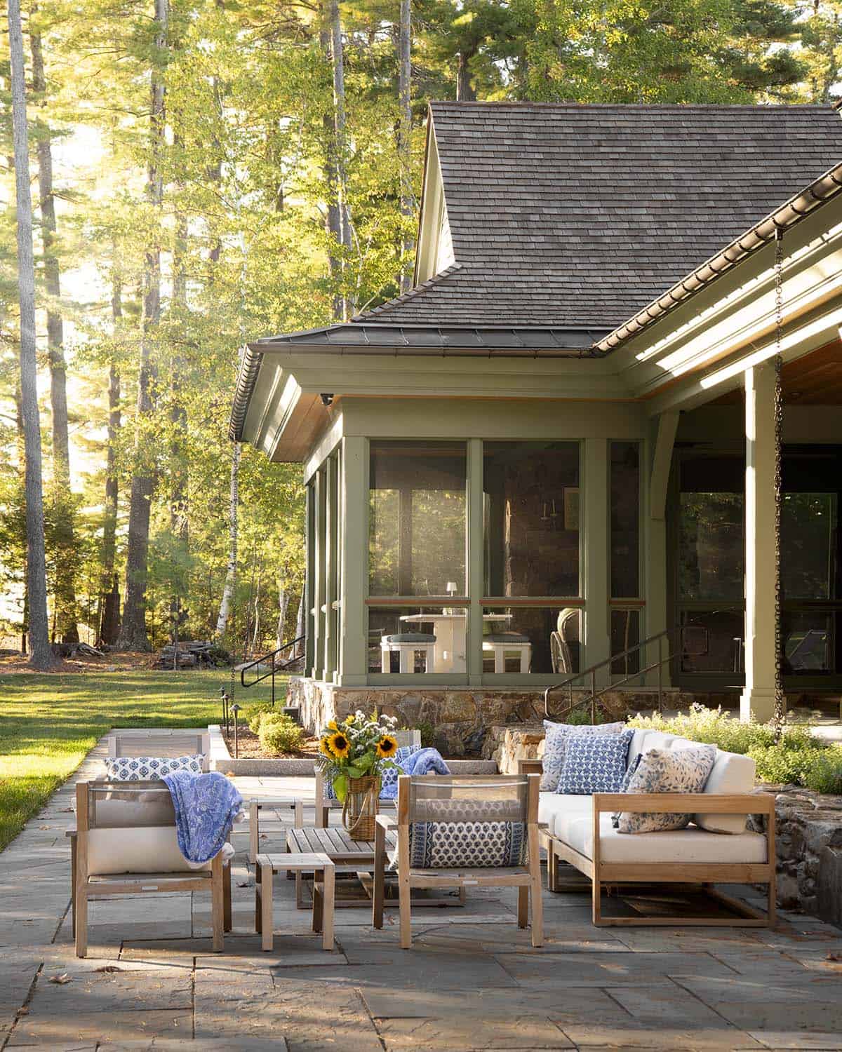 Outdoor stone patio with teak furniture and screened porch at East Cove Estate