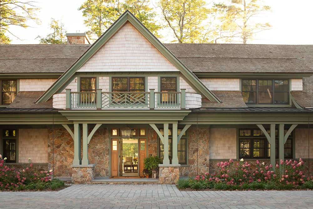 Front entry facade with cedar shingles, stone base, and green timber-frame porte-coch&egrave;re