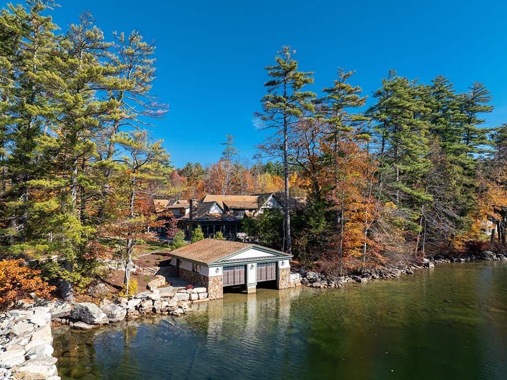 Aerial view of boathouse nestled along Lake Winnipesaukee shoreline in autumn
