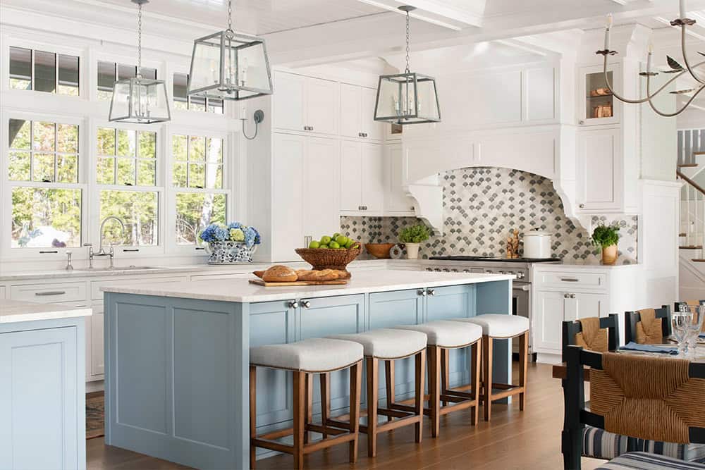 White kitchen with powder blue island, scallop tile backsplash, and lantern pendants