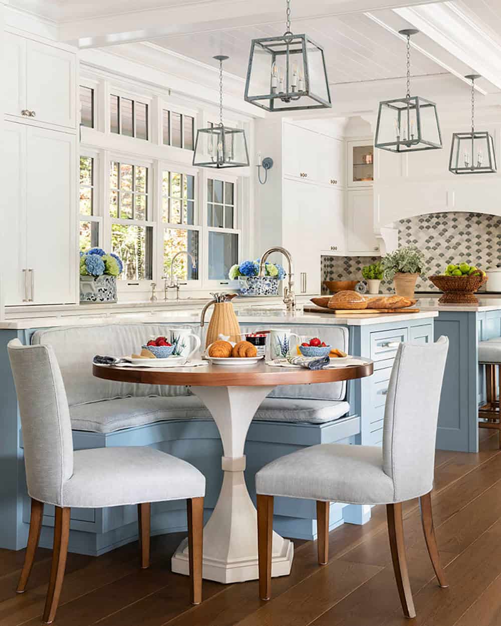 Kitchen banquette nook with round pedestal table and blue island beyond