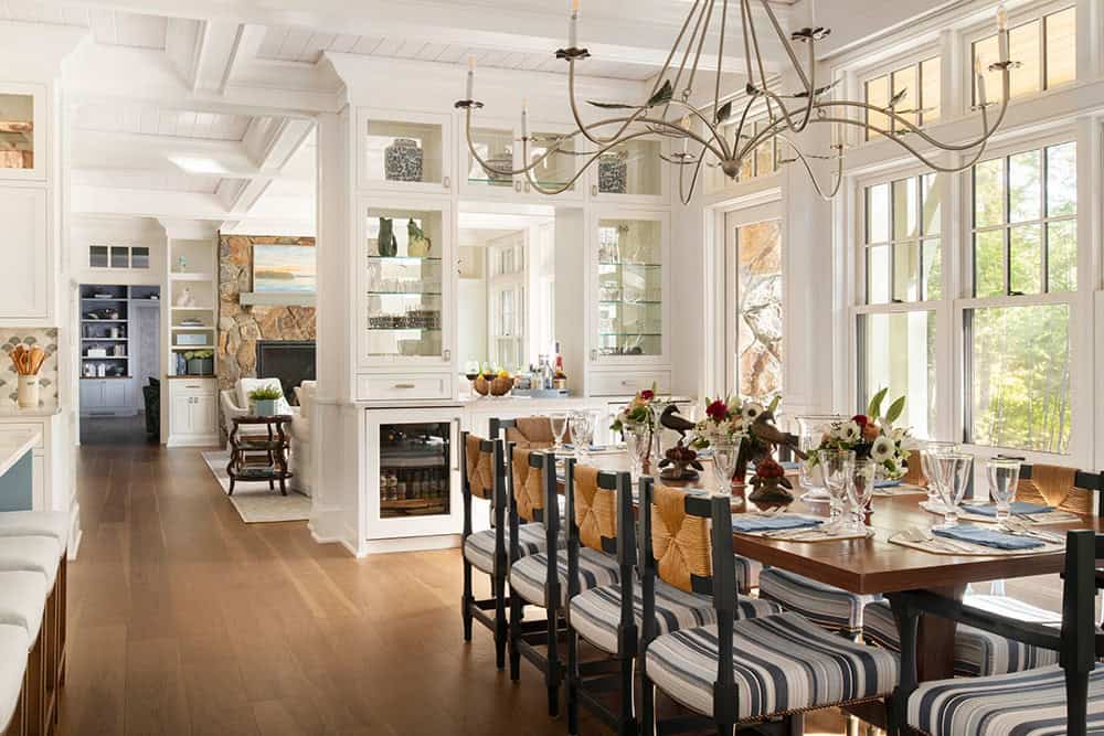 Dining room with striped rush-seat chairs, botanical chandelier, and views to living room