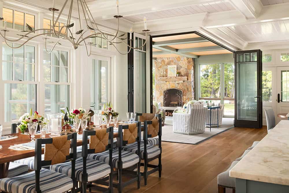 Dining room opening through folding doors to screened porch with stone fireplace