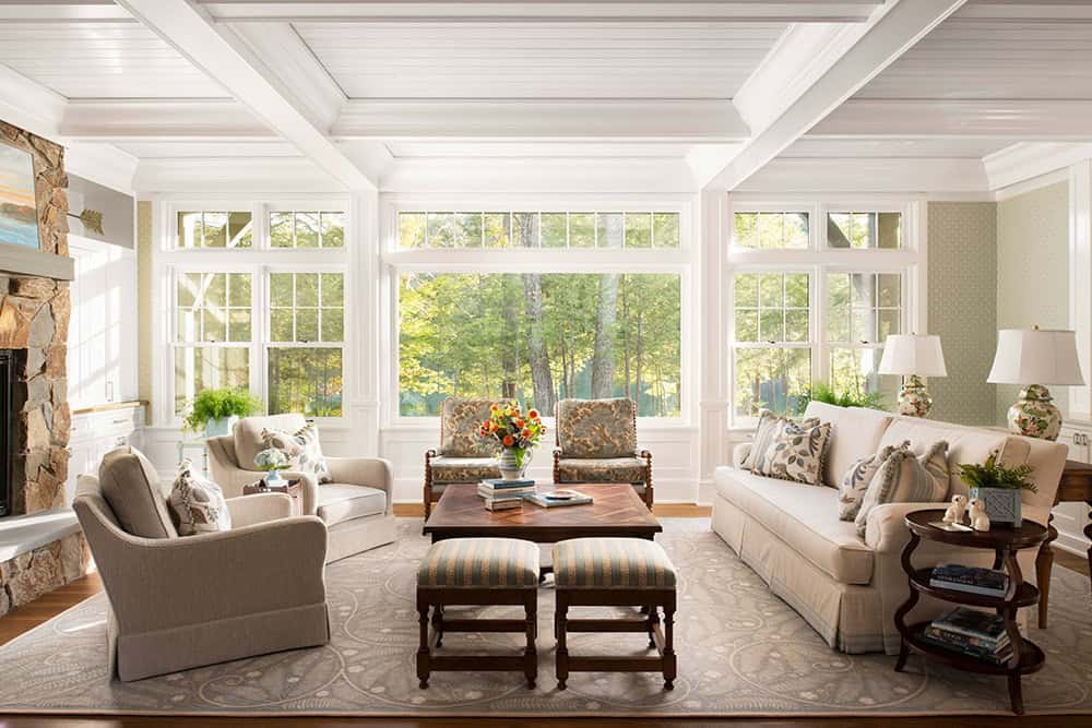 Sunlit living room with coffered ceiling, floor-to-ceiling windows, and neutral furnishings
