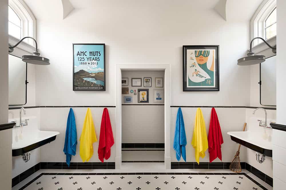 Shared kids' bathroom with black and white tile, dual trough sinks, and colorful towels