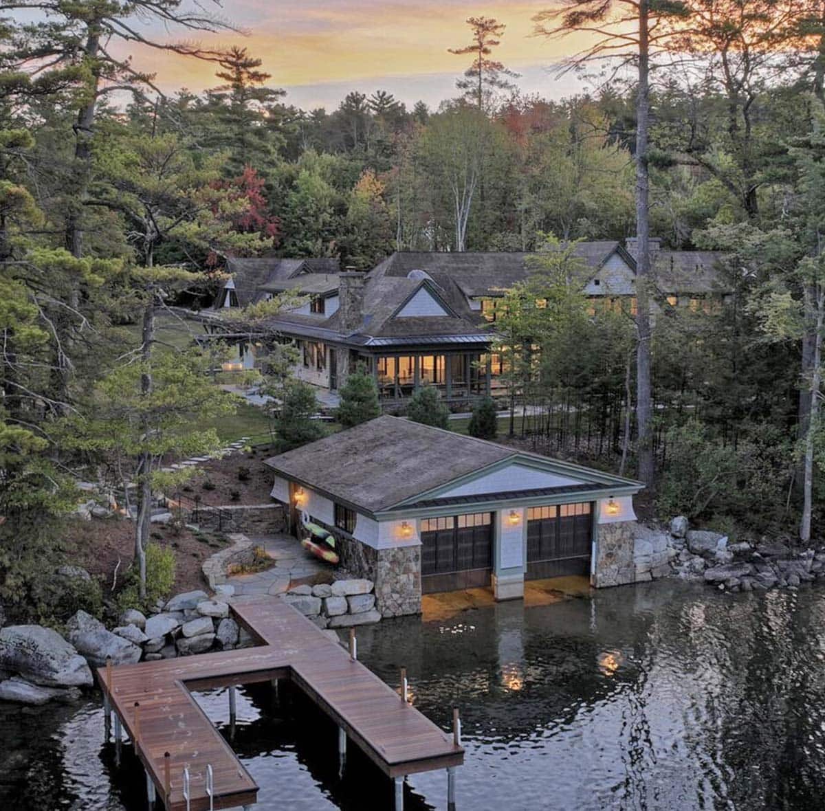 Dusk aerial view of East Cove Estate boathouse and dock glowing on Lake Winnipesaukee