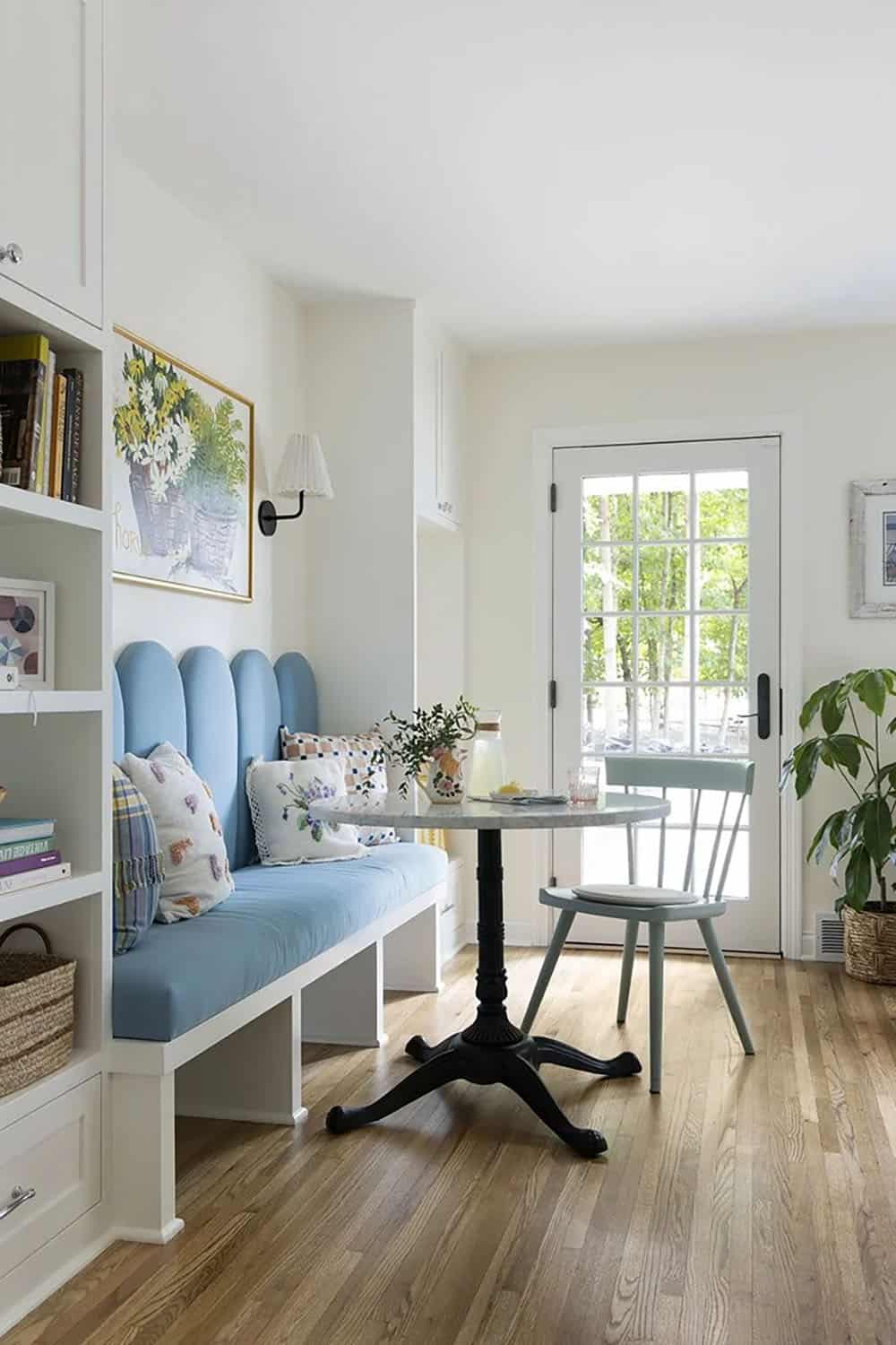 Blue scalloped banquette breakfast nook with round bistro table, mint green chair, and built-in white shelving beside French doors