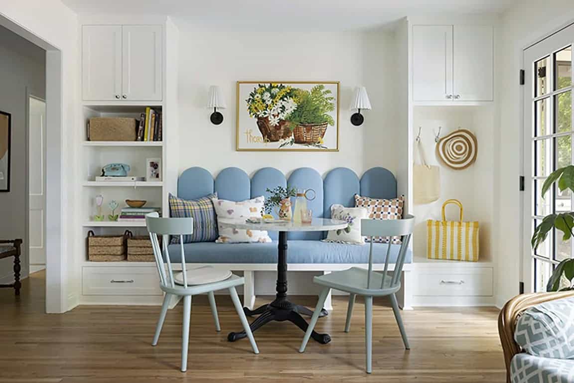 Blue banquette breakfast nook with scalloped back, round bistro table, mint green chairs, and built-in white shelving