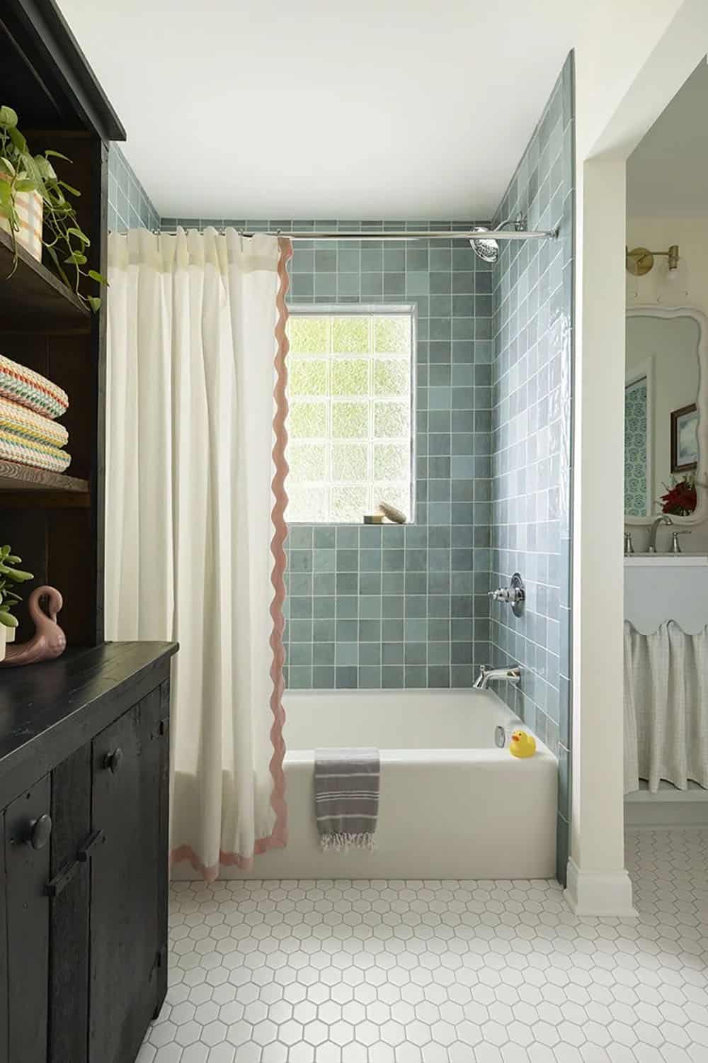 Bathroom with teal square tile shower surround, white hexagon floor tile, dark wood vanity, and ruffled shower curtain