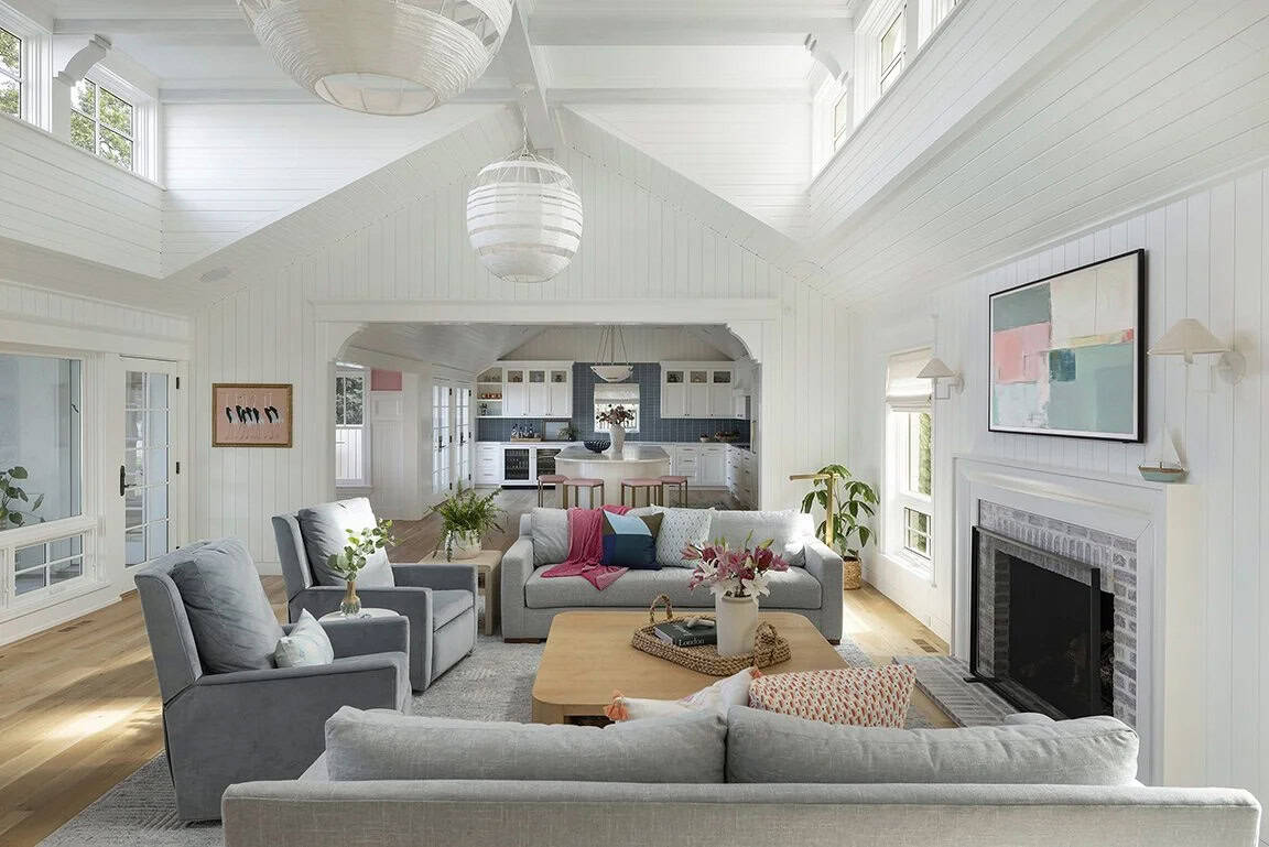 Soaring great room with shiplap vaulted ceiling, gray sectional sofas, arched kitchen pass-through, and globe pendant light
