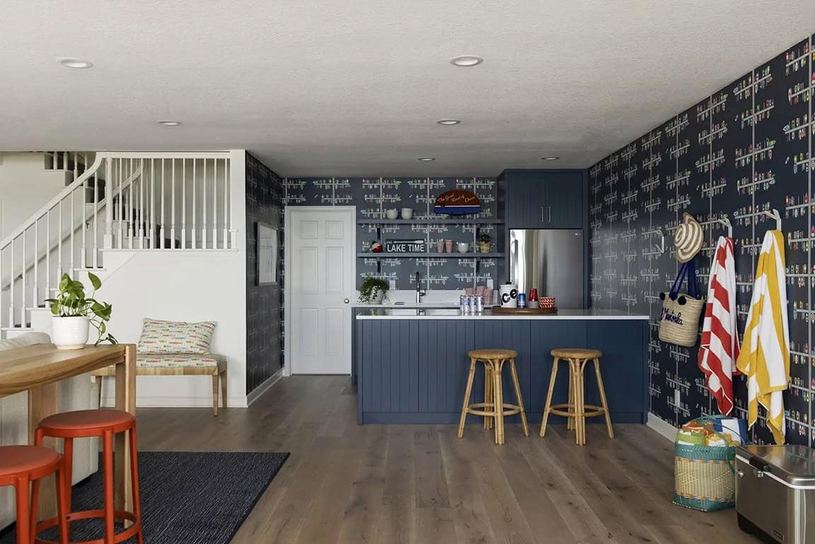 Basement wet bar with navy shiplap island, rattan stools, boat-print wallpaper, open shelving, and beach towel mudroom wall