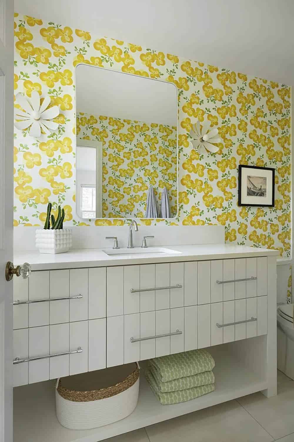 Bathroom with bold yellow floral wallpaper, white floating vanity, flower-shaped sconces, rectangular mirror, and white tile floor