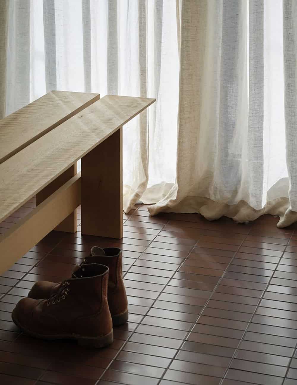 Detail of handcrafted wood bench with leather boots on terracotta tile floor