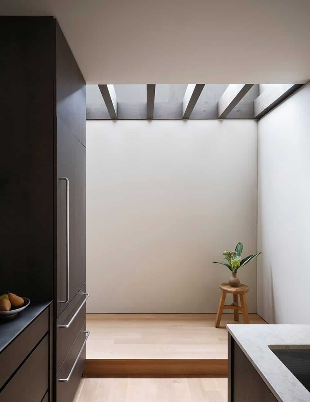 Perimeter skylight above kitchen transition space with exposed beams and wood stool
