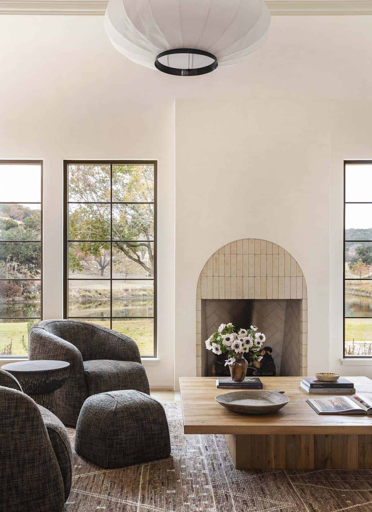 Close-up of arched tile fireplace surround with white anemone flowers and chunky wood coffee table