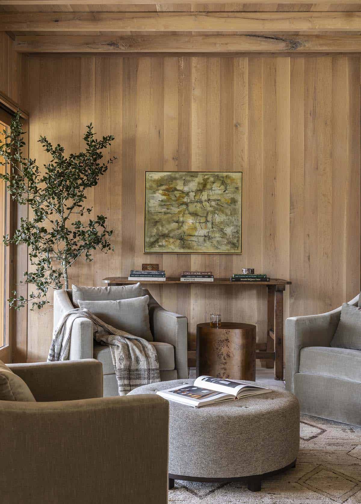 Cozy sitting room with white oak wall paneling, abstract painting, burl wood side table, and swivel chairs