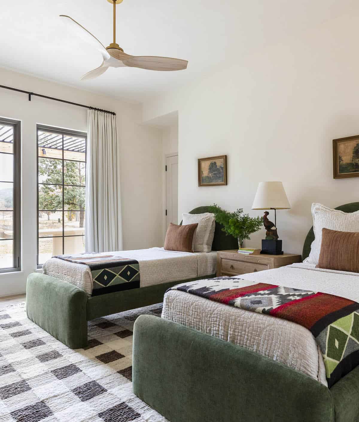 Guest bedroom with two green velvet platform beds, Pendleton-style throws, and patterned area rug