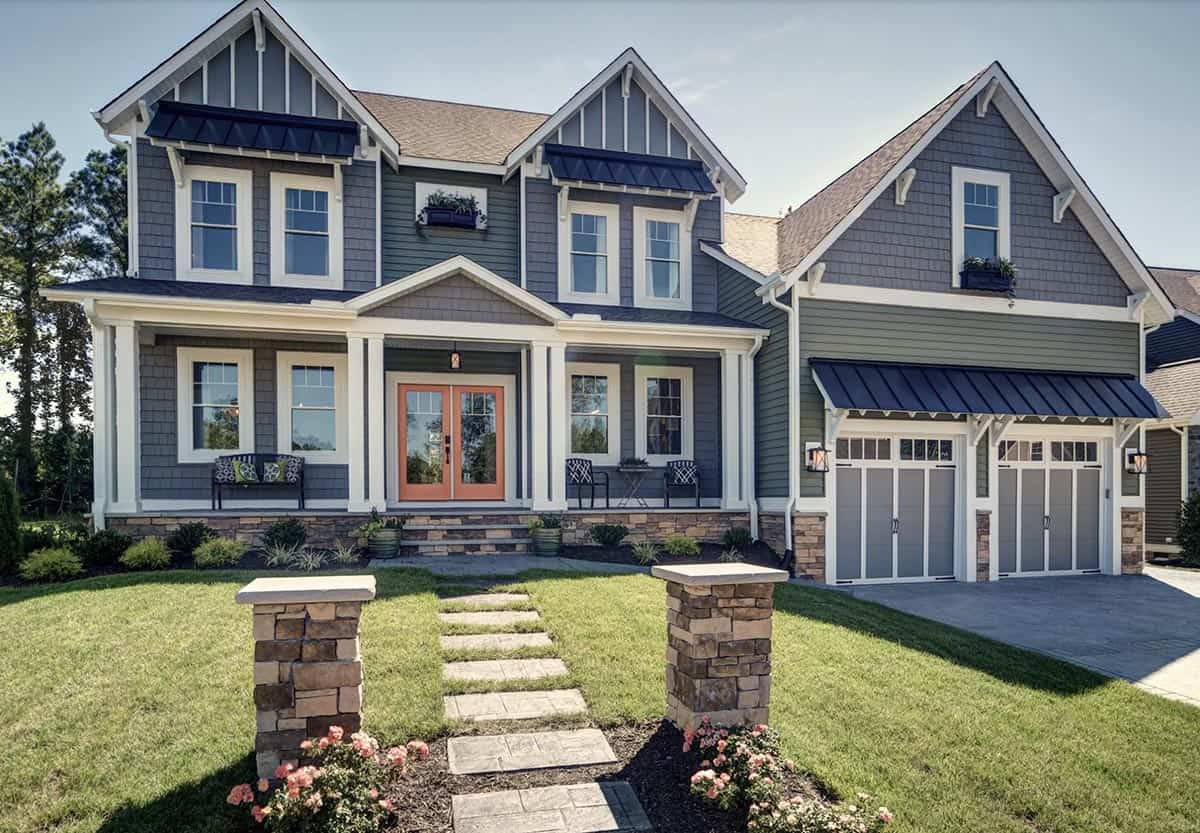 Modern craftsman farmhouse exterior with gray-green shiplap siding, coral front door, covered porch, and stone pillars
