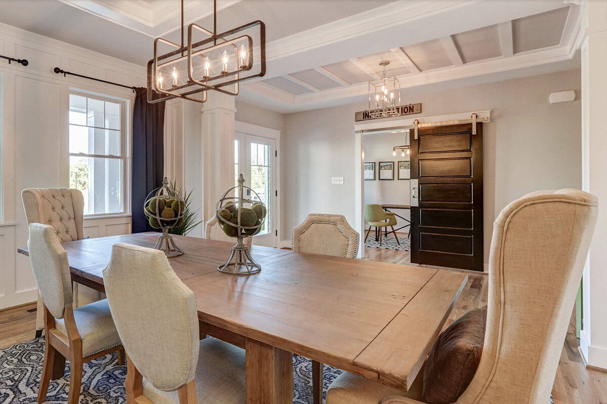 Formal dining room with rustic wood farm table, tufted linen chairs, coffered ceiling, and sliding barn door