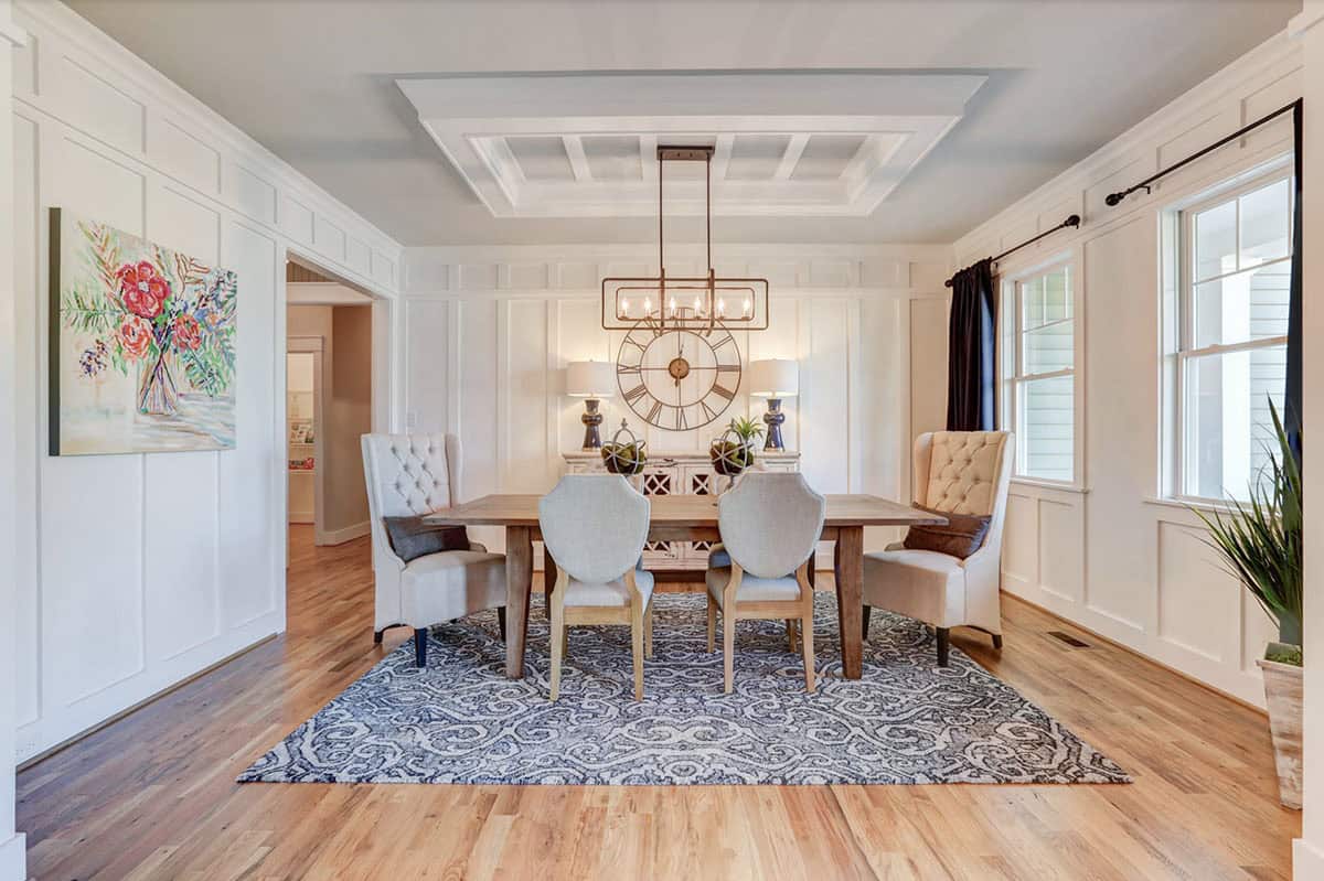 Dining room with full board-and-batten wall paneling, coffered ceiling, blue patterned rug, and large wall clock