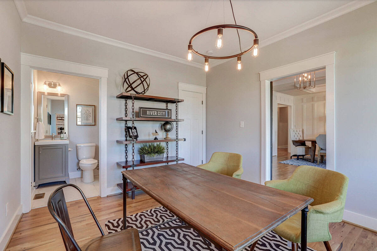 Home office or flex room with industrial chain shelving, Edison bulb chandelier, and green accent chairs