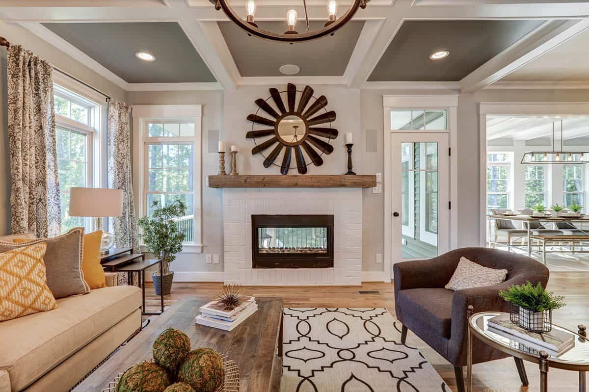 Living room fireplace wall with white painted brick, reclaimed wood mantel, and sunburst mirror above