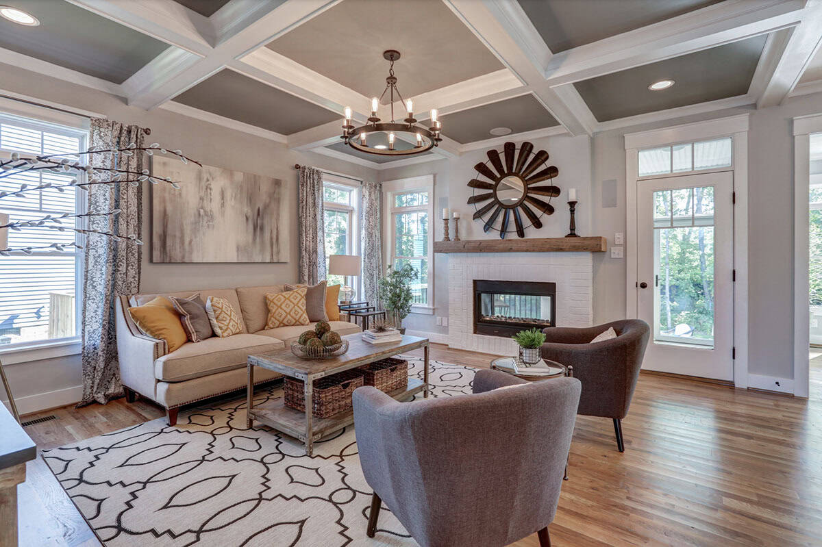 Living room with coffered ceiling, neutral sofa, mustard accent pillows, and white brick fireplace