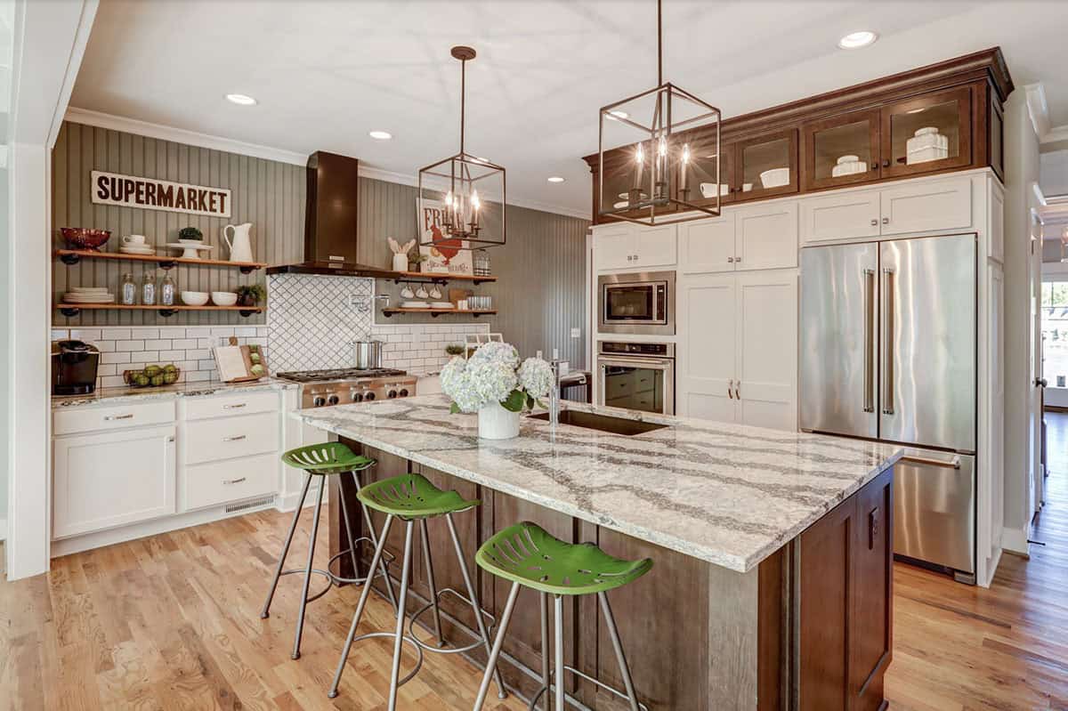 Farmhouse kitchen with white perimeter cabinets, dark wood island, granite countertops, and green tractor-seat barstools