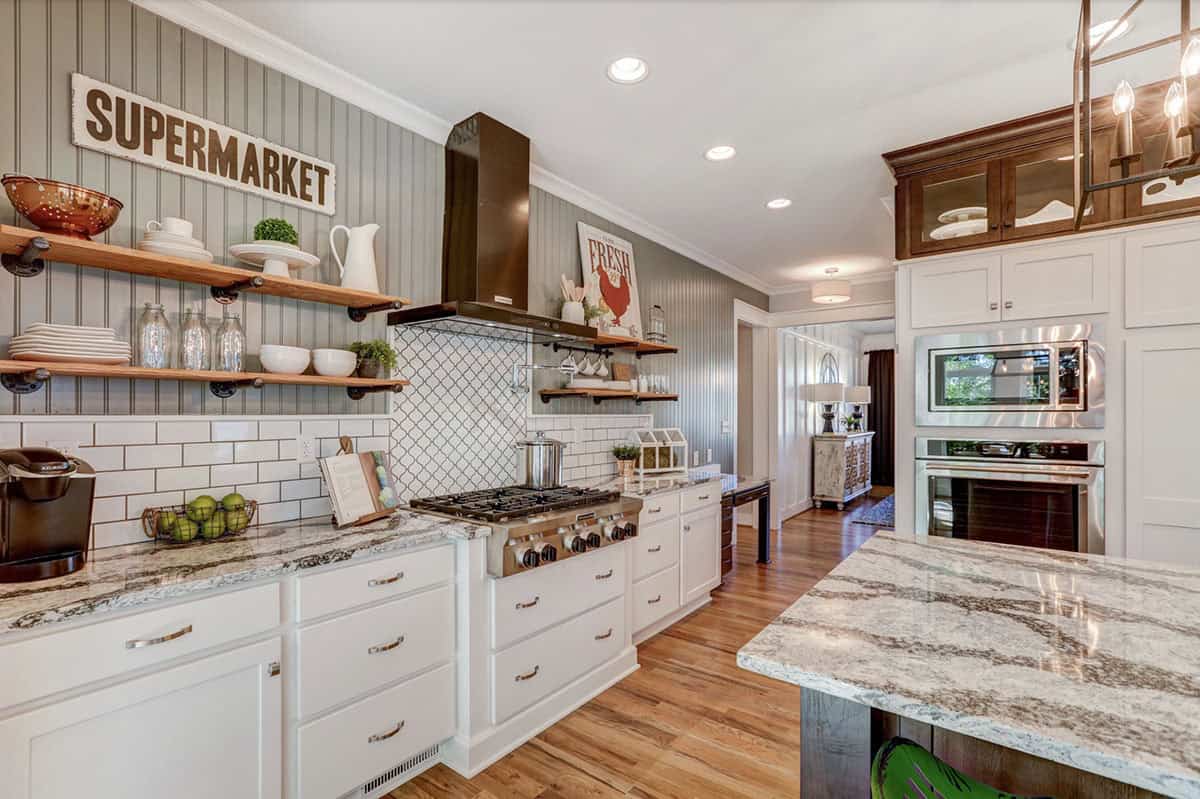 Kitchen cooking wall with gas range, white subway tile, open wood shelving, and beadboard accent wall