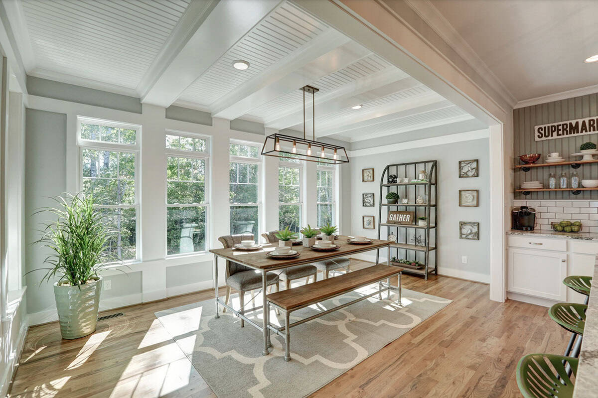 Bright farmhouse breakfast nook with industrial pipe table, bench seating, beadboard ceiling, and large windows