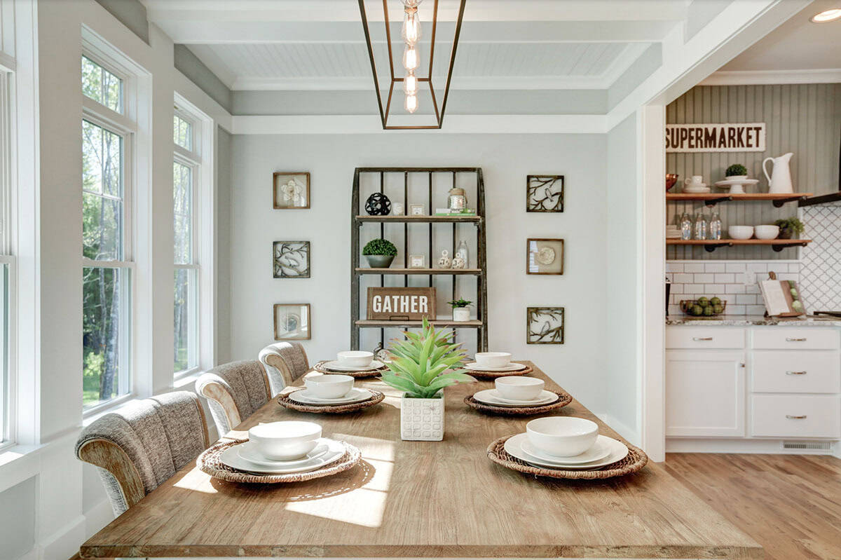 Breakfast nook table set for six with white dishware, rustic shelving unit with Gather sign, adjacent to kitchen