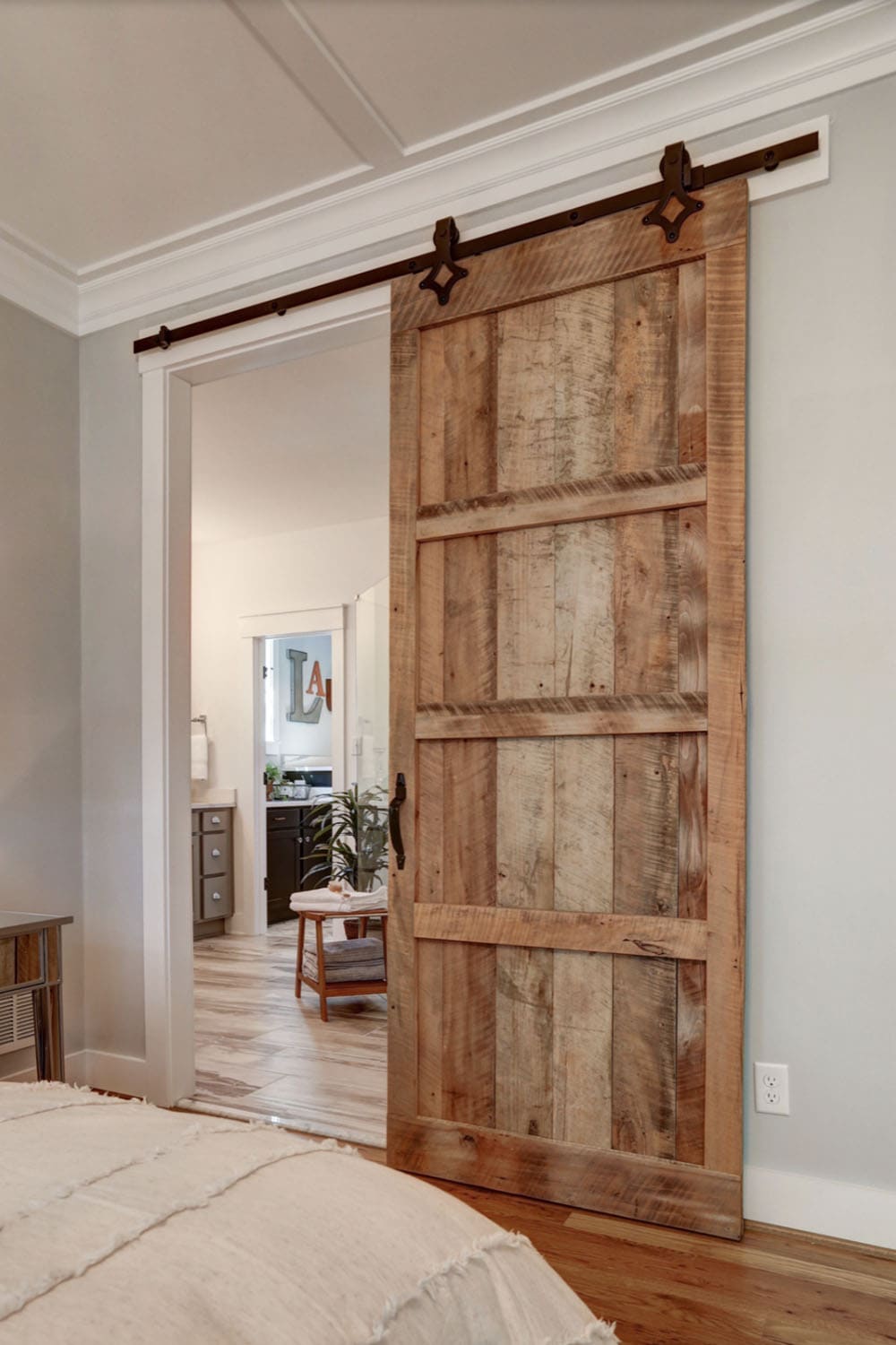 Close-up of reclaimed wood sliding barn door with black iron hardware opening to ensuite bathroom