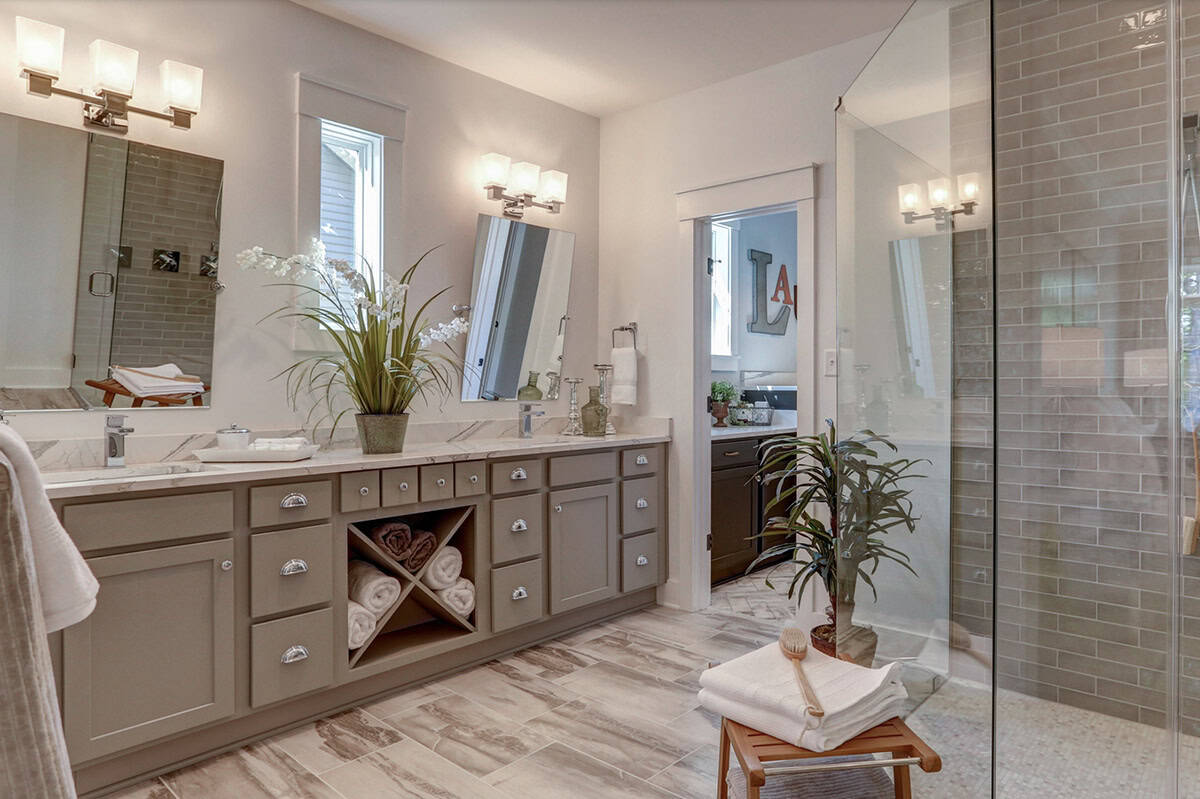 Primary ensuite bathroom with double gray vanity, X-pattern towel cubbies, marble countertop, and glass walk-in shower