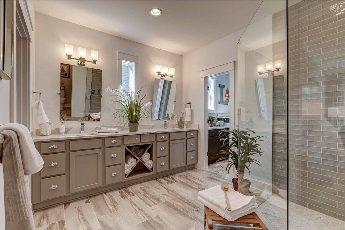 Primary ensuite bathroom with double vanity, gray cabinets, marble counters, and glass shower with gray tile