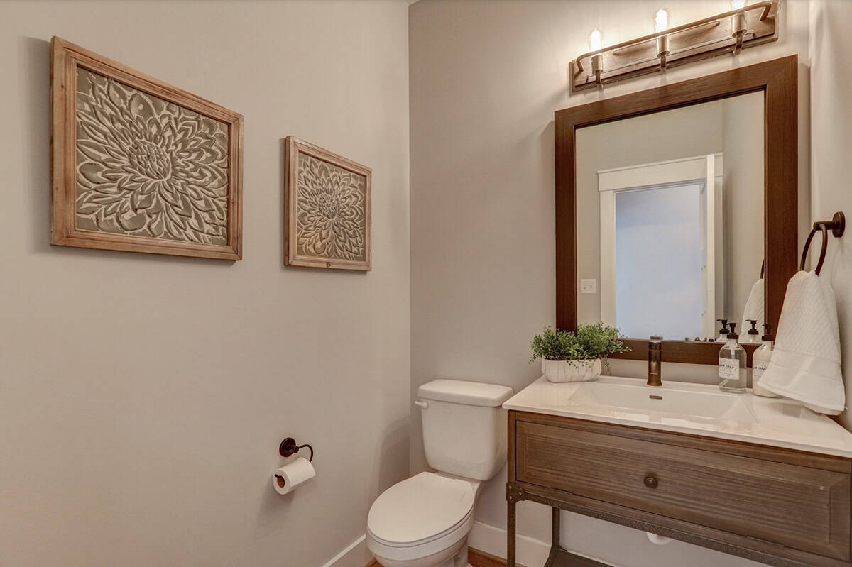 Powder room with wood-framed mirror, rustic vanity, bronze fixtures, and floral wall art panels