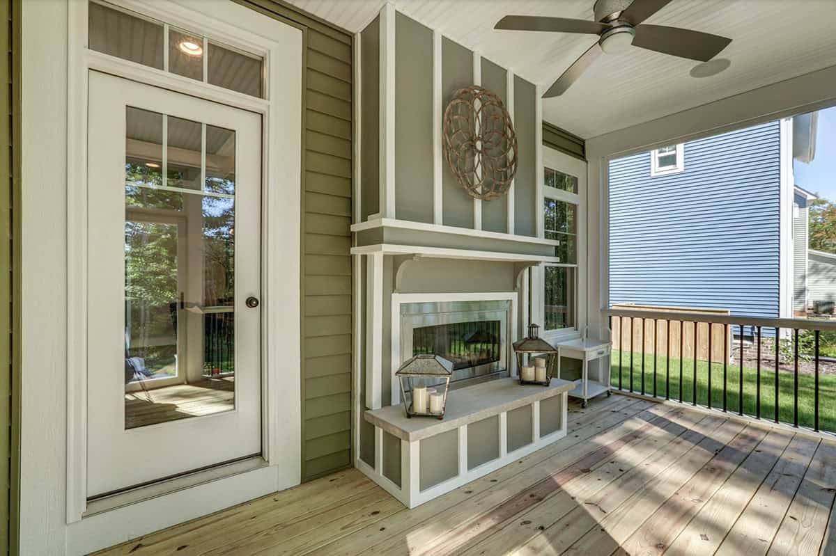 Covered back deck with outdoor fireplace, beadboard ceiling, ceiling fan, and black railing