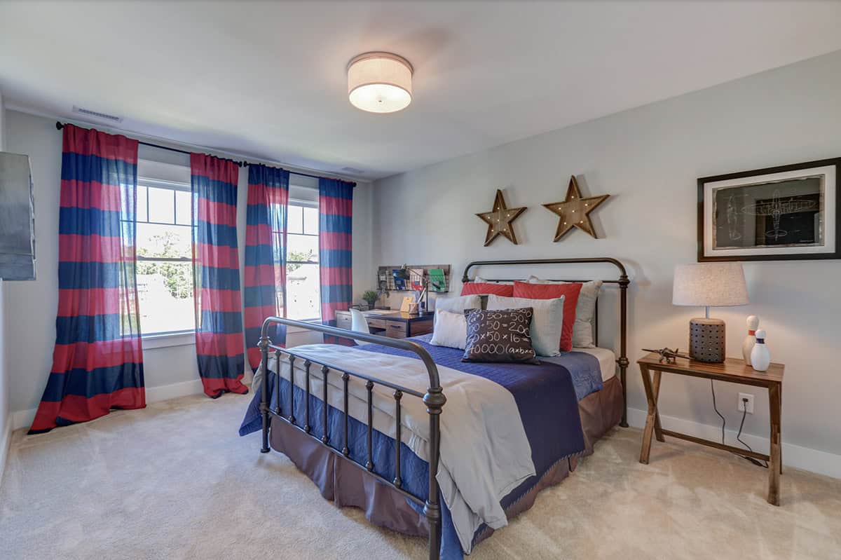 Boys bedroom with black iron bed frame, red and navy striped curtains, and marquee star wall decor