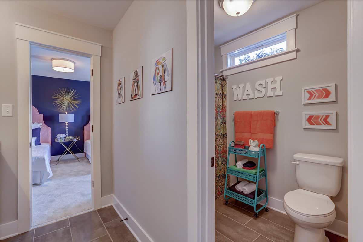 Jack-and-jill bathroom hallway with colorful dog artwork, opening to blue-walled girls bedroom
