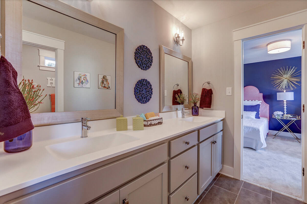 Jack-and-jill double vanity bathroom with gray cabinets, wood-framed mirrors, and view into girls bedroom