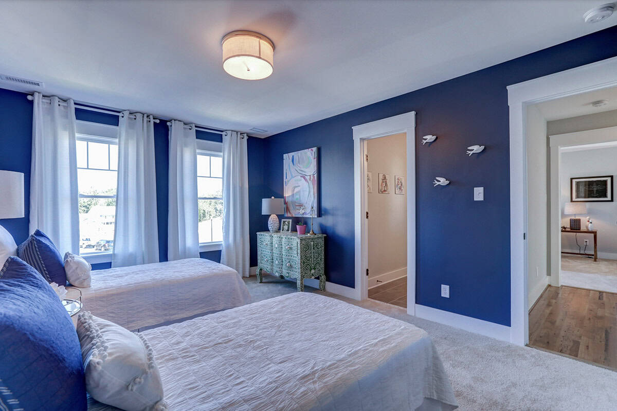Navy blue girls bedroom with twin beds, teal painted dresser, white curtains, and bird wall sculptures