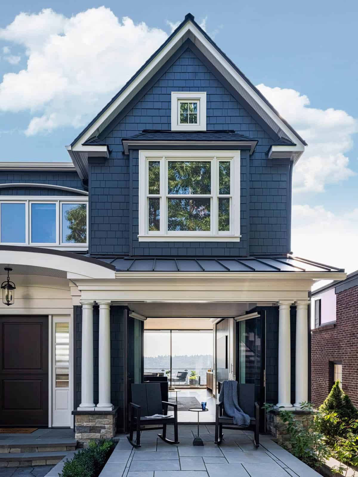 Rear view of craftsman home featuring covered porch with rocking chairs and city water views