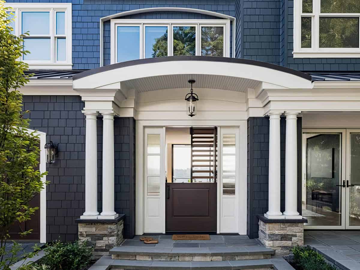 Close-up of craftsman front entry with white Doric columns, arched portico, and dark wood door