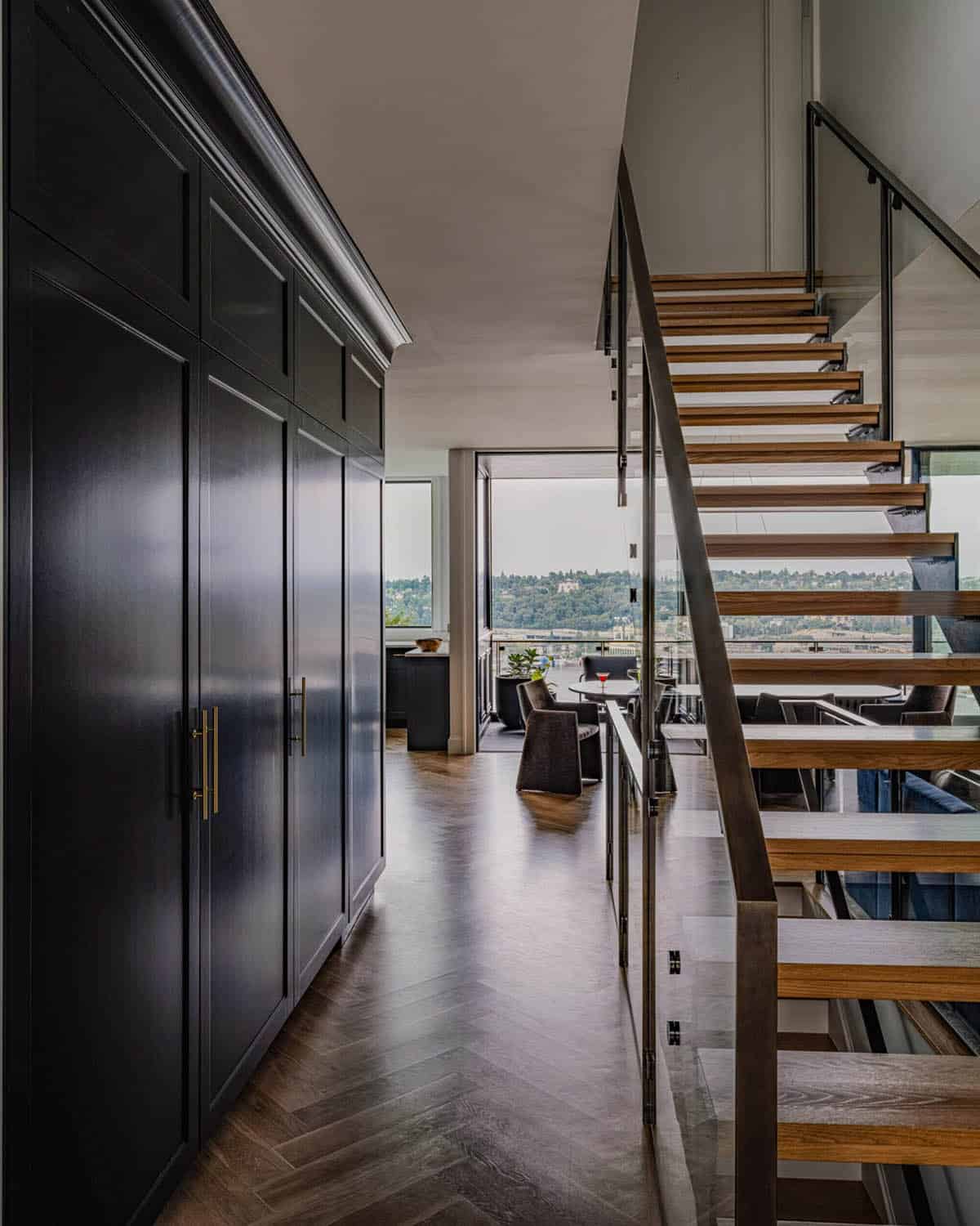 Entryway hallway with dark navy built-in cabinetry, herringbone wood floors, and floating staircase