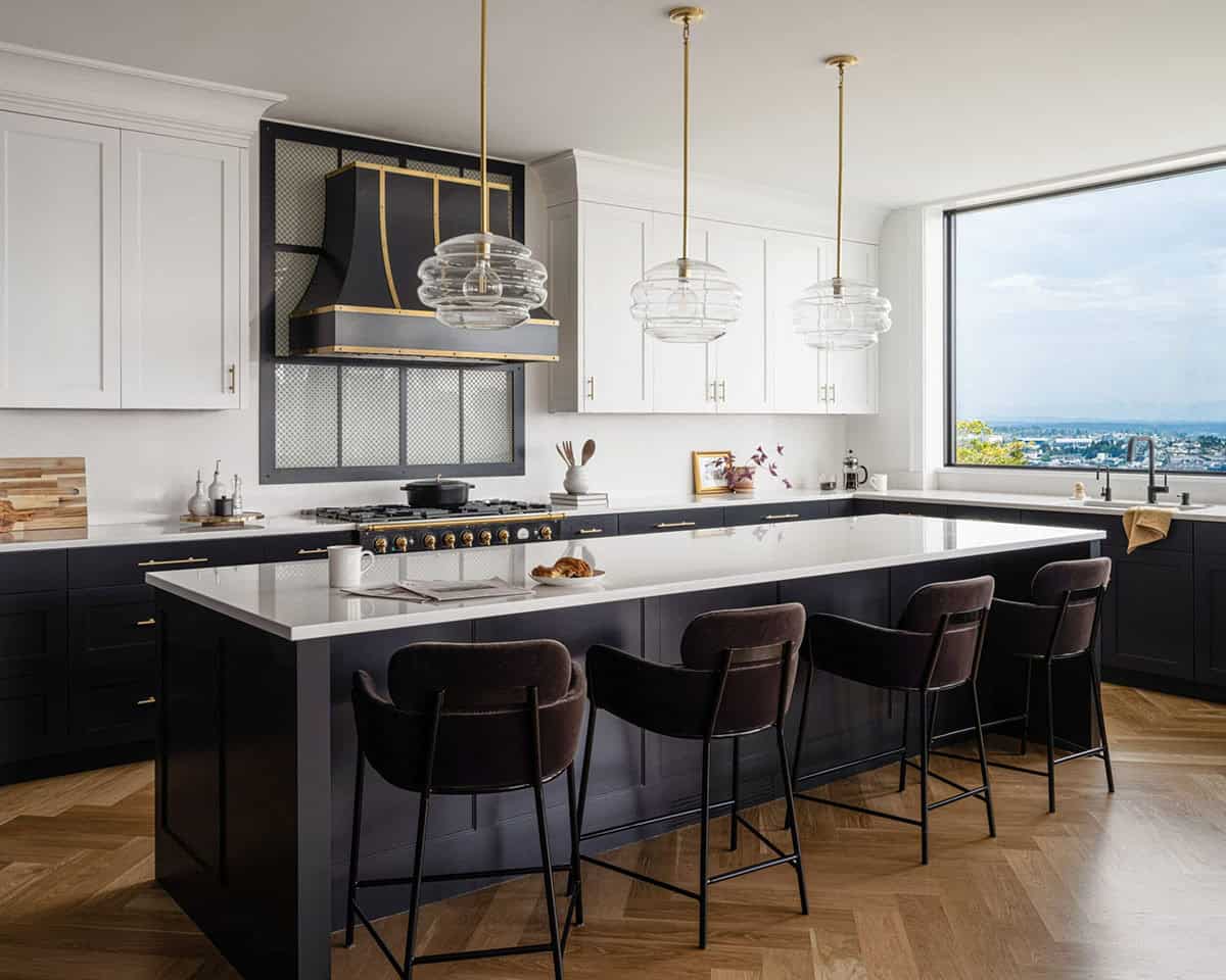 Dark navy kitchen with white island, glass pendant lights, and large picture window overlooking city