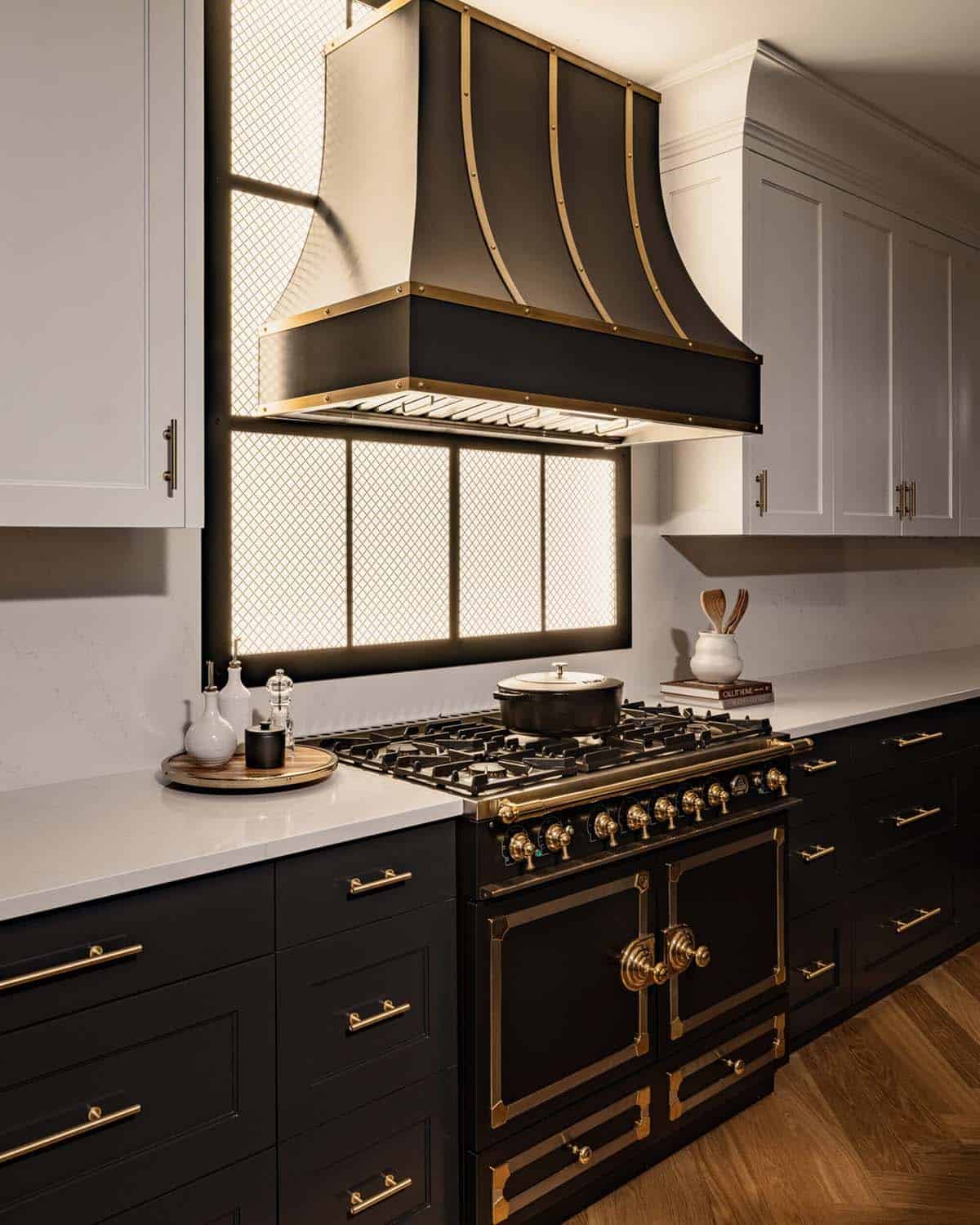 Close-up of dramatic black and brass range hood over luxury gas range with dark cabinetry