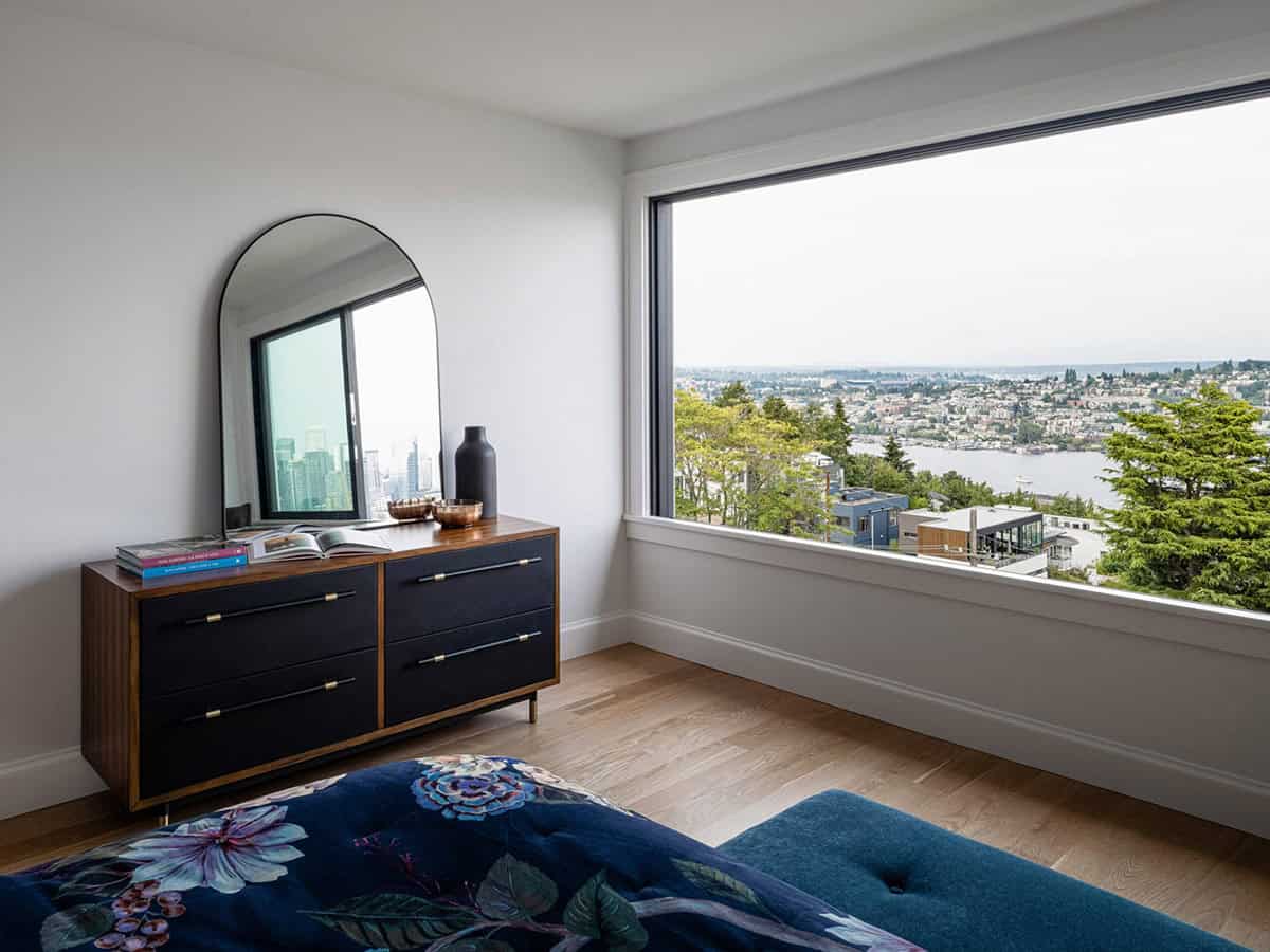 Bedroom dresser corner with arched mirror and oversized picture window overlooking lake and city